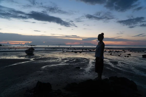 Silueta femenina al atardecer, mujer de pie en la playa del mar . — Foto de Stock