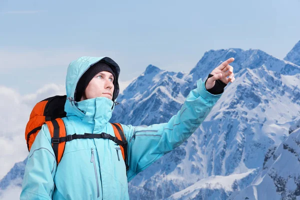 O montanhista apontando para o pico, de pé contra uma paisagem de montanha de inverno . — Fotografia de Stock