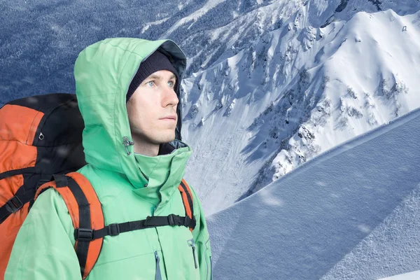 Man alpinist looks up against a winter mountain landscape. — Stock Photo, Image