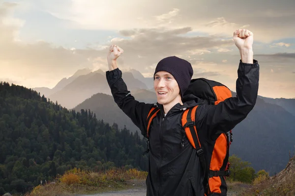Uomo escursionista con lo zaino alzato le mani contro un paesaggio di montagna tramonto . — Foto Stock
