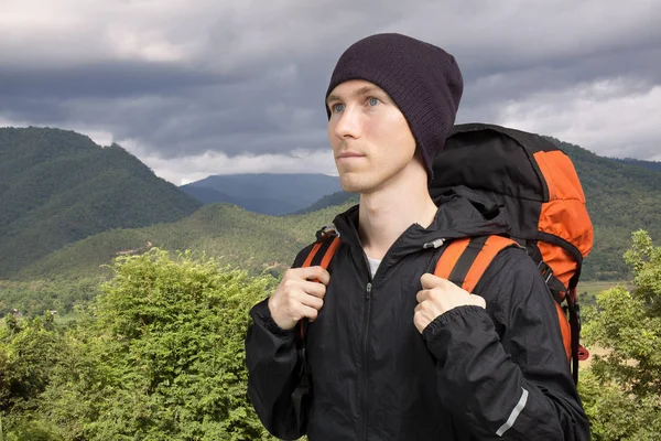 Jeune homme avec sac à dos debout contre un paysage de montagne . — Photo