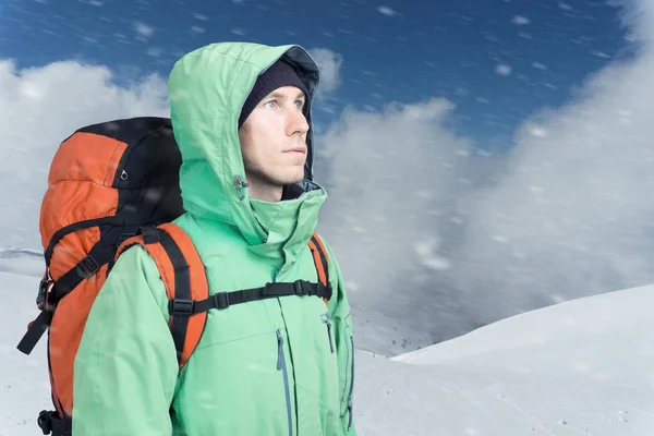 Man alpinist looks up against a winter mountain landscape. — Stock Photo, Image