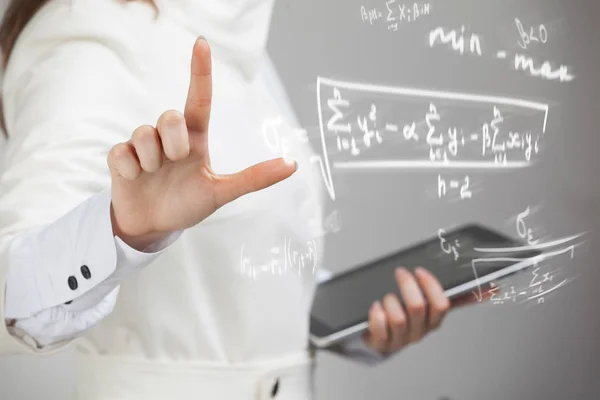 Wissenschaftlerin oder Studentin, die mit verschiedenen mathematischen und naturwissenschaftlichen Formeln arbeitet. — Stockfoto