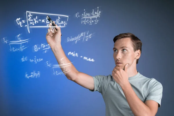 Muž vědec nebo student pracuje s různými vzorci střední školy matematika a věda. — Stock fotografie