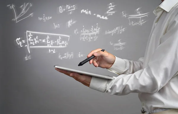 Homem cientista ou estudante segurando tablet PC e trabalhando com várias matemáticas do ensino médio e fórmulas de ciência . — Fotografia de Stock