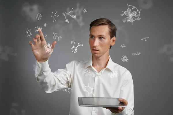 Hombre científico con PC tableta trabajando con fórmulas químicas sobre fondo gris . — Foto de Stock