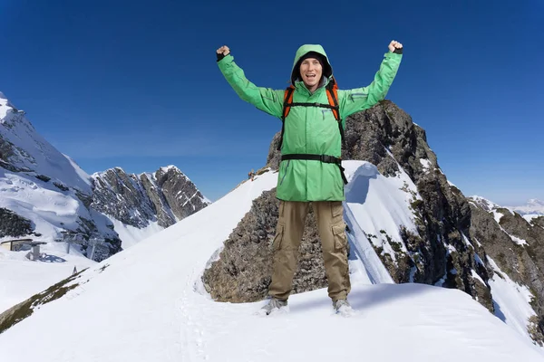 Человек с рюкзаком стоит на снежном склоне горы. Альпинист или альпинист . — стоковое фото