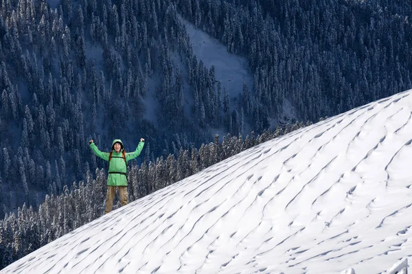 Szczęśliwy młody człowiek z plecaka stojący na ośnieżonym stoku góry. Alpinista lub góry wycieczkowicz. — Zdjęcie stockowe