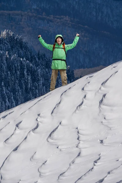 Szczęśliwy młody człowiek z plecaka stojący na ośnieżonym stoku góry. Alpinista lub góry wycieczkowicz. — Zdjęcie stockowe
