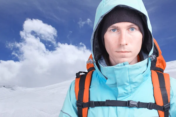 Portrét mladého muže horolezec v zimních horách. Modrou oblohu a bílé mraky — Stock fotografie