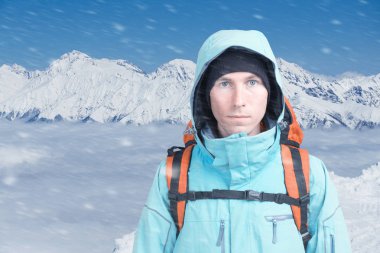 Bir adamla kışın karlı dağlar sırt çantası. Dağcı standları bulutların üstünde.