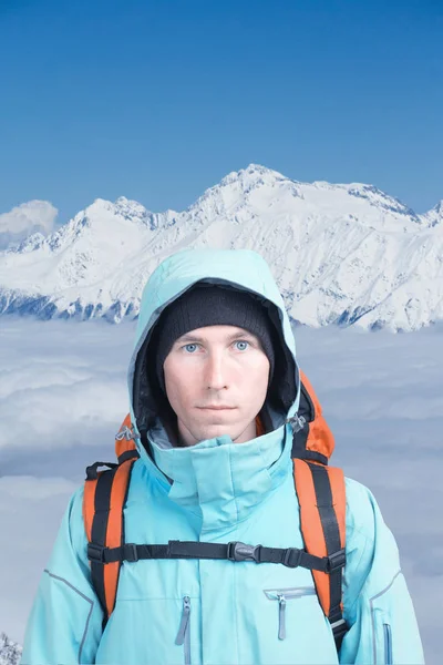 男は雪の山冬のバックパックします。雲の上の登山家スタンド. — ストック写真