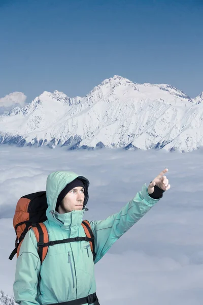 男は雪の山冬のバックパックします。雲の上の登山家スタンド. — ストック写真