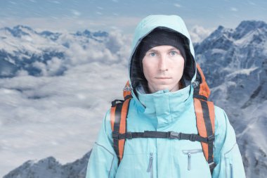 Bir adamla kışın karlı dağlar sırt çantası. Dağcı standları bulutların üstünde.