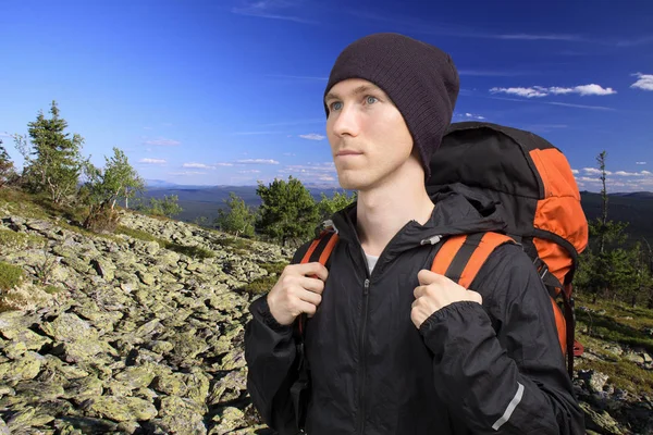 Homem com mochila em pé no topo de uma montanha e olha para a distância. Turismo de montanha, aventura e viagens . — Fotografia de Stock