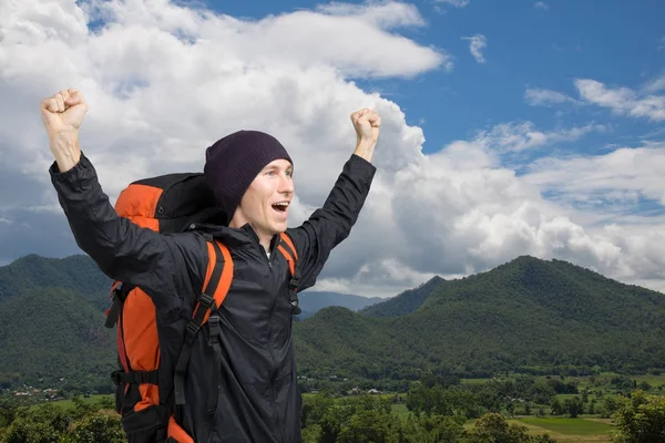 Joven con la mochila de pie en la cima de una montaña con las manos arriba . —  Fotos de Stock