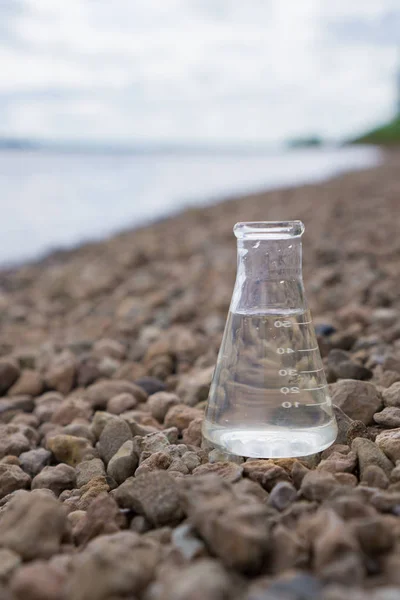 Su, göl veya nehir içinde belgili tanımlık geçmiş ile kimyasal şişesi. — Stok fotoğraf