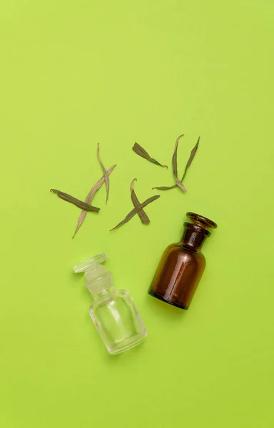 Ervas secas e dois frascos vazios no fundo verde. Medicina à base de plantas, óleo essencial. Conceito de medicina alternativa. Fundo com espaço de cópia . — Fotografia de Stock