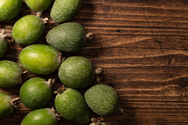 Feijoa fruits lying on textured wooden surface. Background, banner, header — 图库照片