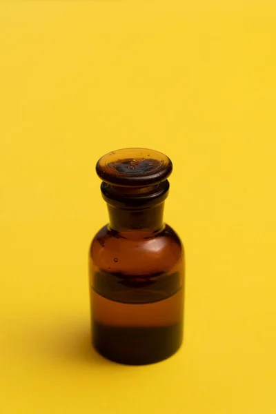 Garrafa de vidro no fundo amarelo. Perfume, medicina, química de fundo . — Fotografia de Stock