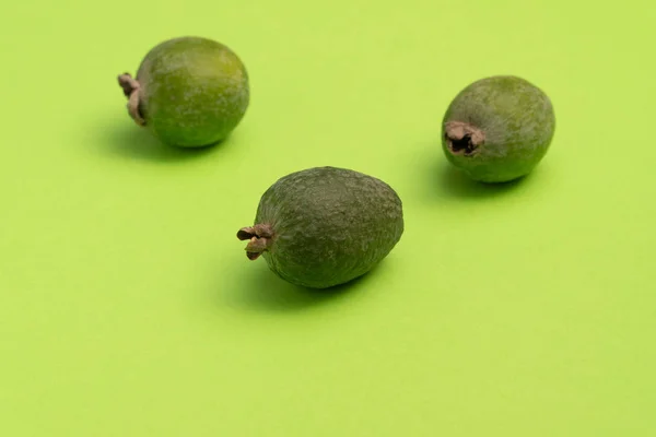 stock image Three fresh feijoa fruits on bright green surface. Studio close-up shot.