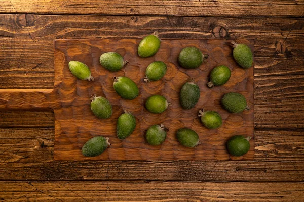 Feijoa fruits lying on textured wooden surface. Background, banner — 图库照片