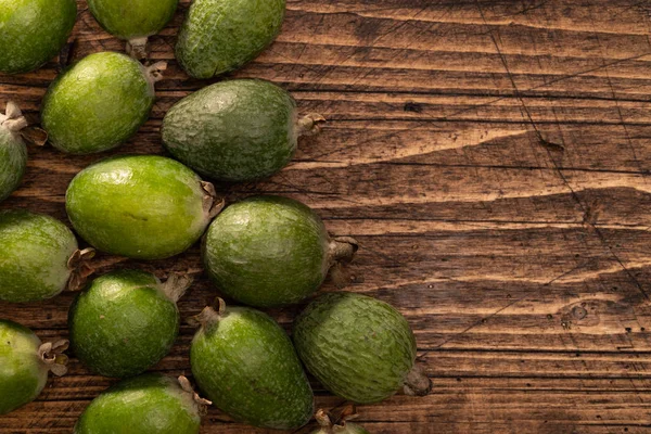 Feijoa fruits lying on textured wooden surface. Background, banner, header — 图库照片