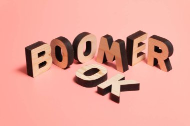 Tamam Boomer. İnternet mim 'i gençler arasında popüler. Pembe arka planda ahşap kelimeler.