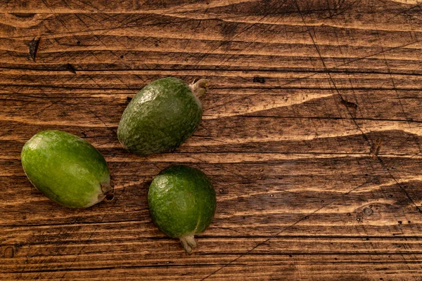 Feijoa fruit liggend op getextureerd houten oppervlak. Achtergrond, banner, header — Stockfoto