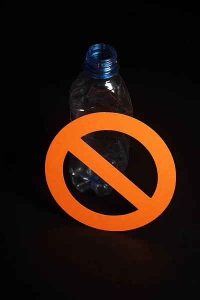 Botol plastik biru kosong dengan tanda berhenti di latar belakang hitam. Konsep penghentian polusi plastik, daur ulang plastik, bebas plastik . — Stok Foto