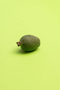 Parlak yeşil yüzeyde taze feijoa meyvesi. Stüdyo yakın çekim.