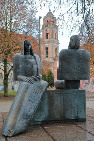 VILNIUS, LITUÂNIA - JANEIRO 2, 2017: Estátuas de Sofija Psibiliauskiene e Marija Lastauskiene na Rua Karmelitu com o campanário da Igreja de Todos os Santos em segundo plano — Fotografia de Stock