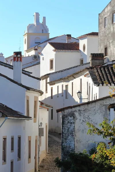 Marvao, Portugália: Egy jellegzetes macskaköves utcán, fehérre meszelt házak és csempézett tetők az Óratorony, a háttérben — Stock Fotó