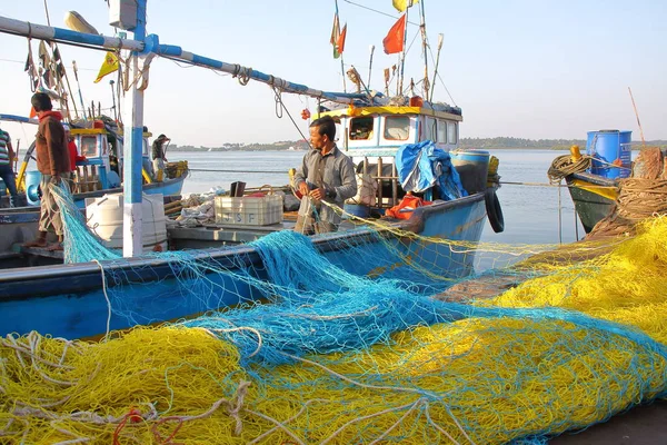 DIU, INDIA - 9 DE ENERO DE 2014: Pescador trabajando en su red de pesca en el puerto pesquero de Vanakbara, en la isla de Diu — Foto de Stock