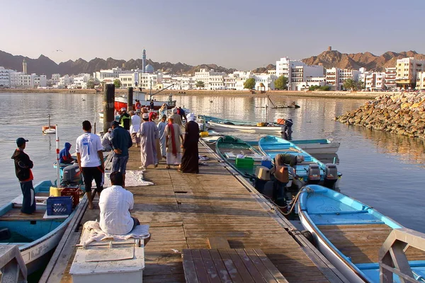 Muscat, Oman - 11 februari 2012: Fiskare på The Muttrah Fish docks tidigt på morgonen med Muttrah corniche i bakgrunden — Stockfoto