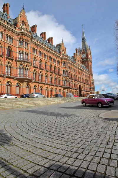 LONDRES, Reino Unido - 28 DE FEBRERO DE 2017: Vista exterior de la estación de tren de St Pancras con un pavimento empedrado y un coche clásico púrpura en primer plano. Este edificio ahora alberga el lujoso St Pancras Renaissance Hotel — Foto de Stock