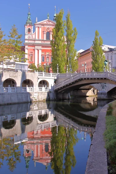 LJUBLJANA, SLOVENIA: Reflections of The Church of The Annunciation and the Triple Bridge in the river Ljubljanica — Stock Photo, Image