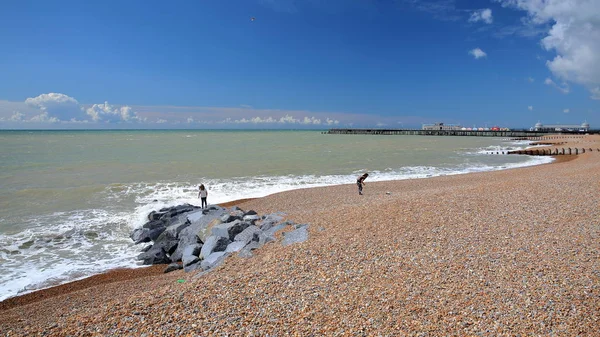 A praia colorida de Hastings com o cais (reconstruído e aberto ao público em 2016) no fundo e um céu azul com nuvens agradáveis, Hastings, Reino Unido — Fotografia de Stock