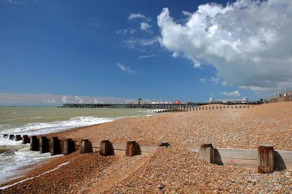 A praia colorida de Hastings com o cais (reconstruído e aberto ao público em 2016) no fundo e um céu azul com nuvens agradáveis, Hastings, Reino Unido — Fotografia de Stock