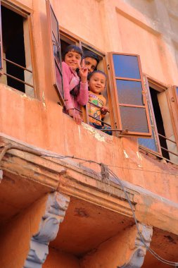 Jodhpur, Rajasthan, Hindistan - 17 Aralık 2017: Gülümseyen ve kameraya kendi penceresinden bakıyor çocuk portresi