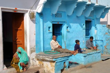Chittorgarh, Rajasthan, Hindistan - 13 Aralık 2017: Geleneksel evlerinin dışında güneşin tadını insanlar ile renkli sokak sahne