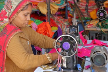 CHITTORGARH, RAJASTHAN, INDIA - DECEMBER 13, 2017: Close-up on a tailor woman working on her sewing machine inside her shop in the Old Town clipart