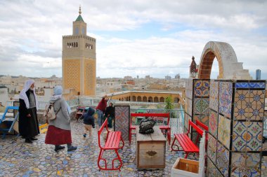Tunus, Tunus - 29 Aralık 2019: Medine 'ye tepeden bakan renkli fayanslı teras, Ez Zitouna Camii (Büyük Cami) minaresi ve geleneksel olarak giyinmiş yerel bir aile