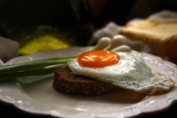 Натюрморт с вкусной яичницей, хлебом и зеленым луком — стоковое фото