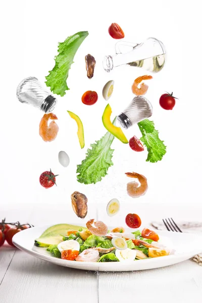 Levitación de Deliciosa ensalada de verduras apetitosas con mariscos en un plato blanco . — Foto de Stock