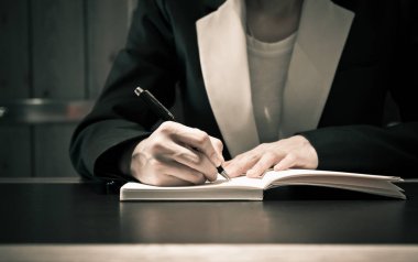 Close up of business people hand in suit writing on notebook or document clipart