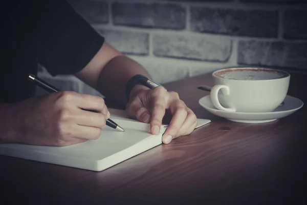 Close up de pessoas mão escrevendo no notebook na mesa de madeira — Fotografia de Stock