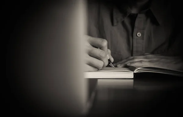 Close up de pessoas mão escrevendo no notebook na mesa de madeira — Fotografia de Stock