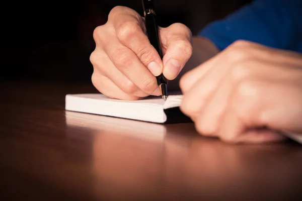 Close up de pessoas mão escrevendo no notebook na mesa de madeira — Fotografia de Stock