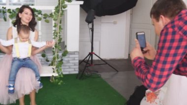 Baba, karısı ve oğlunun güzel bir evin ön cephesinde sallanırken fotoğraflarını çeker.